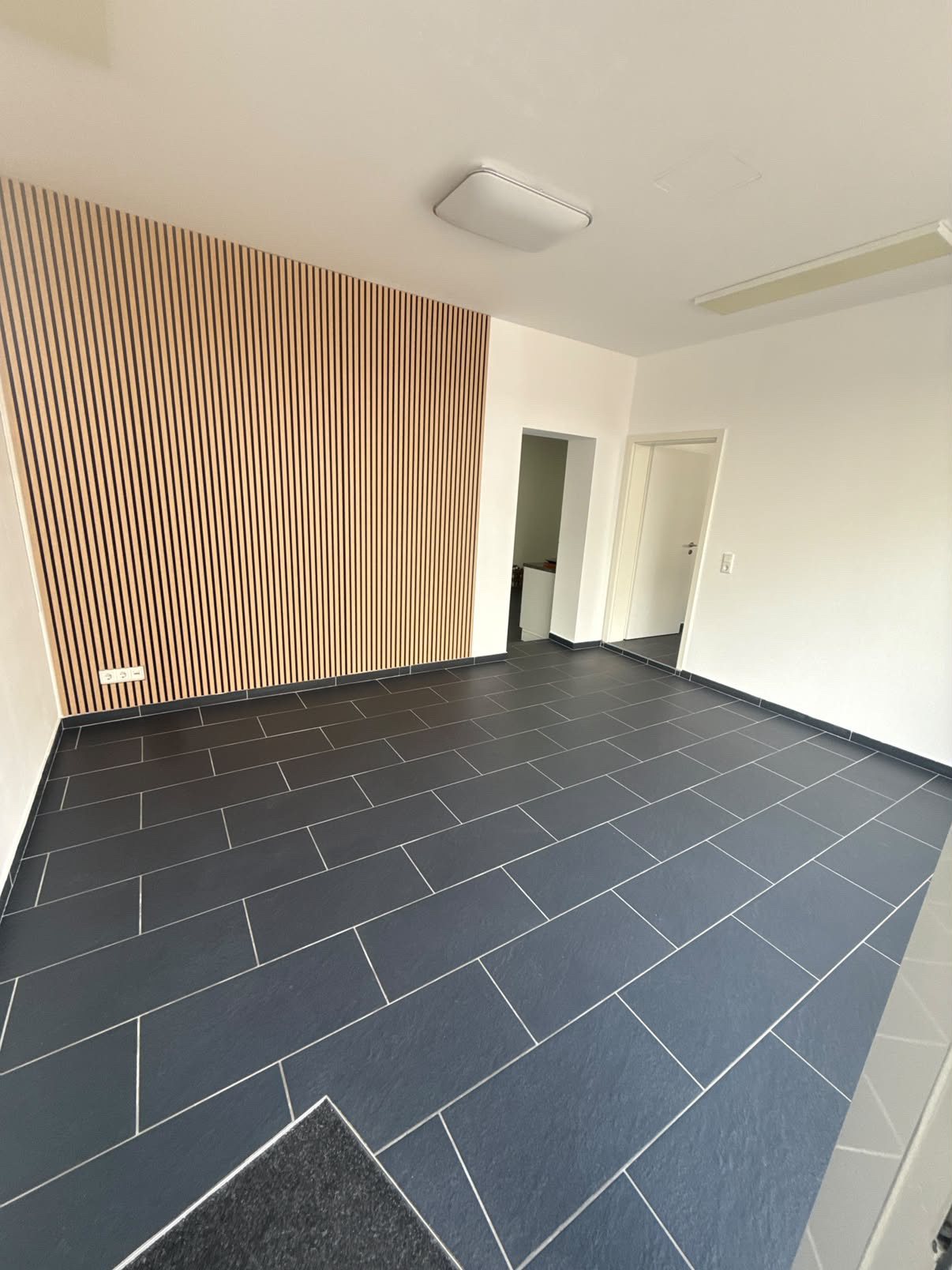 Frisch gereinigter Büroraum mit dunklen Fliesen und Holzlamellen-Wand
