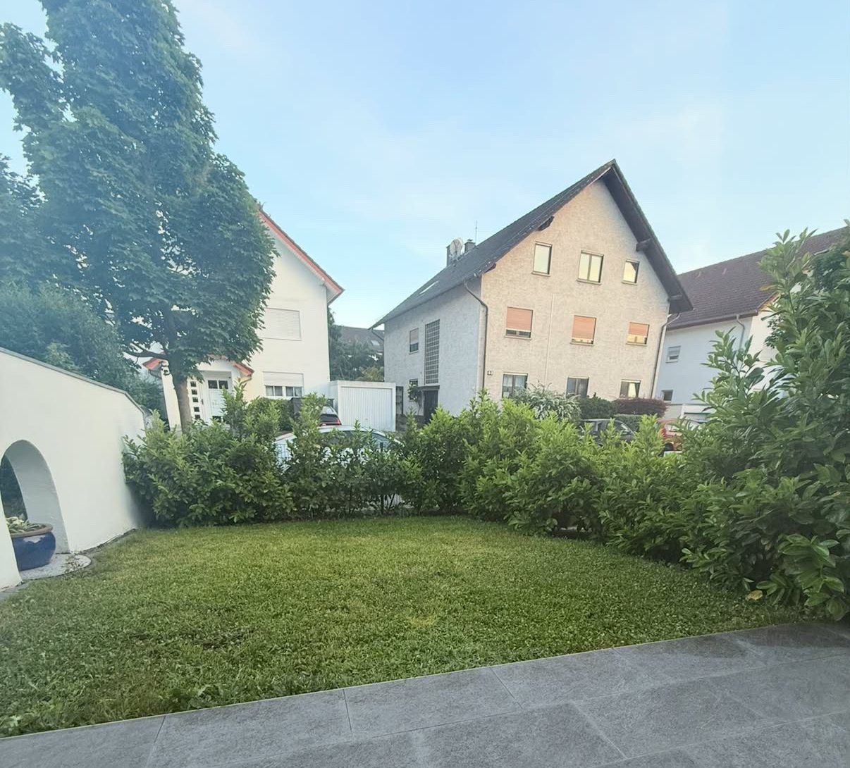 Gepflegter Rasen mit Kirschlorbeerhecke vor einer Terrasse